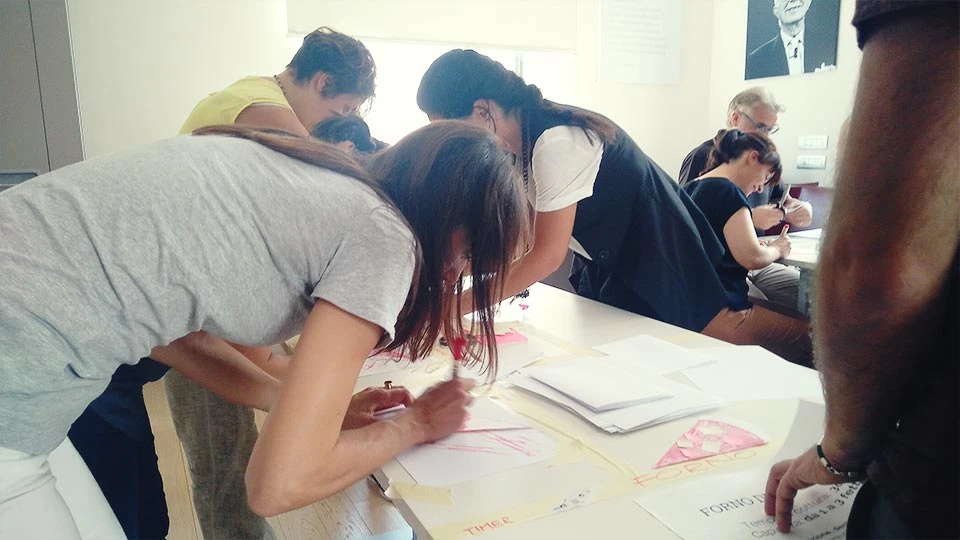 People standing around a table writing on paper sheets